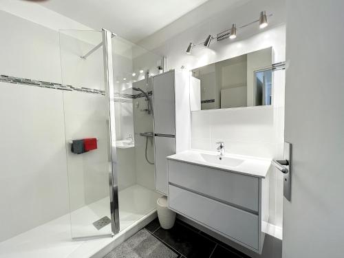 uma casa de banho branca com um lavatório e um chuveiro em VILLA MAUPASSANT BORD DE MER em Cannes