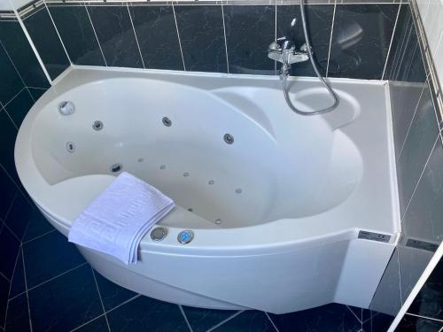 a white bath tub in a bathroom with a towel at Villa Skenderija east by Poppy Sarajevo in Sarajevo