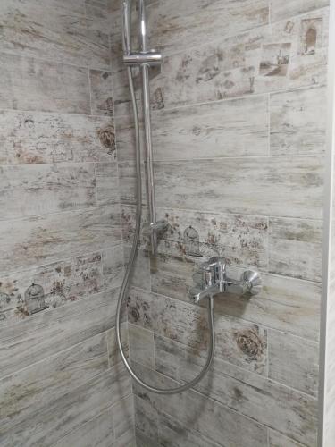 a shower in a bathroom with a stone wall at Вила Христови in Bŭlgarevo