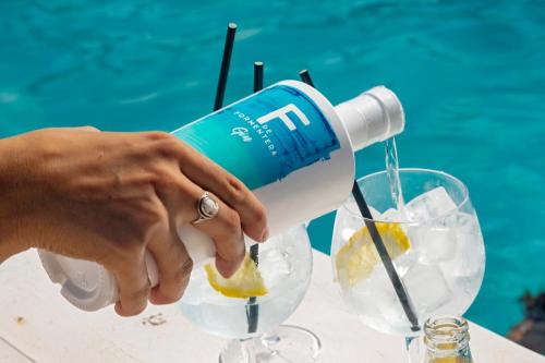 a person pouring a drink into a glass at Hotel Maysi in Playa Migjorn