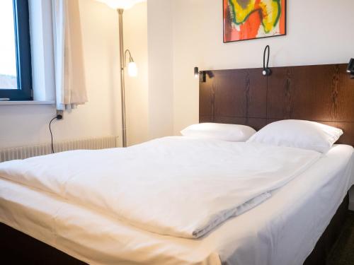 a large white bed with white sheets and pillows at Hotel Europa in Aabenraa