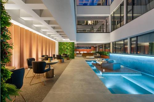 a hotel lobby with a pool and tables and chairs at The Emporium Hotel Plovdiv MGallery Collection in Plovdiv