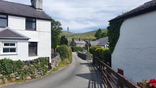 Green Cottage - Snowdonia في Llanllechid: شارع قرية به بيوت بيضاء وسياج