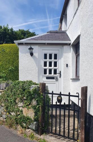 a white house with a gate and a white door at Green Cottage in Llanllechid