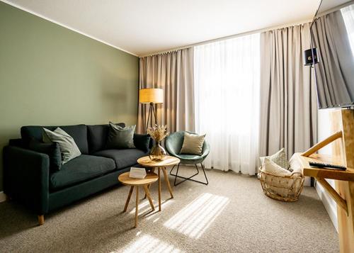 a living room with a green couch and chairs at Waldhotel Eiche in Burg