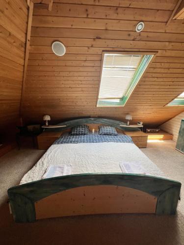 a bed in a wooden room with a window at B&B Chardas in Bük