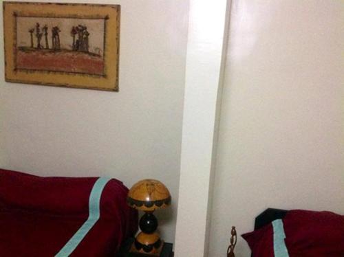 a living room with a red couch and a lamp at Hotel Kavana in Ouagadougou