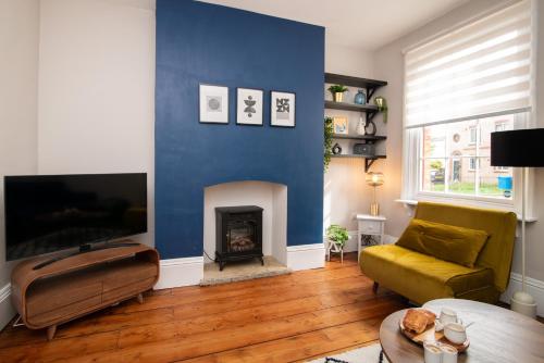 una sala de estar con una pared azul con chimenea en Railway Cottage with garden & parking in heart city en Derby