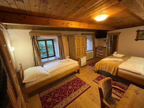 a bedroom with two beds in a room with wooden ceilings at Ubytování Elias in Černá v Pošumaví