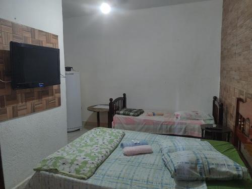 a bedroom with two beds and a flat screen tv at Pousada Brilho do Sol in Guarujá