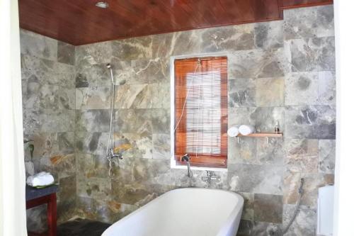 a bathroom with a bath tub and a window at Hoi an Osaka Riverside Villa & Spa in Hoi An