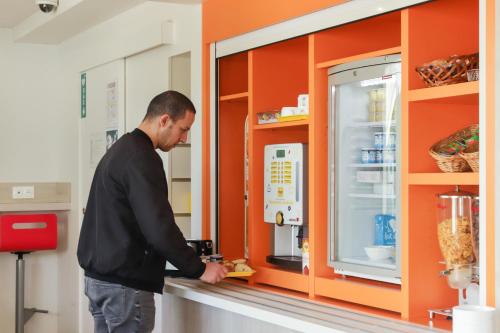 a man standing at a counter in front of a refrigerator at Premiere Classe Lyon Beynost in Beynost