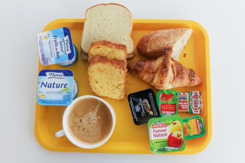 a yellow plate of food with toast and a cup of coffee at Premiere Classe Lyon Beynost in Beynost
