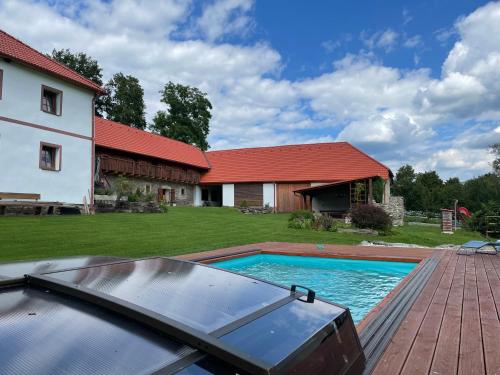 un patio trasero con piscina y una casa en Farma Náhlov, en Frymburk