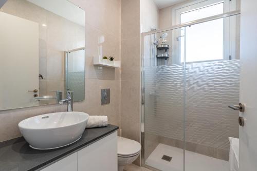 a bathroom with a sink and a glass shower at Lemon Tree 1-BR Apt in Livadia in Larnaka