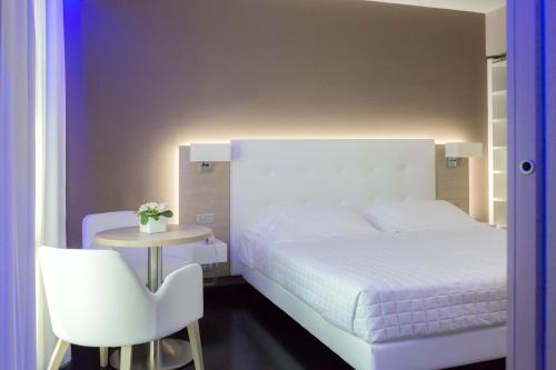a bedroom with a white bed and a table and a chair at Raffaello Hotel & Mooka Restaurant in Senigallia