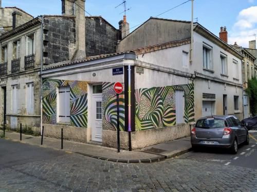 samochód zaparkowany przed budynkiem z graffiti w obiekcie Charmante maison T2 au Centre de Bordeaux w mieście Bordeaux
