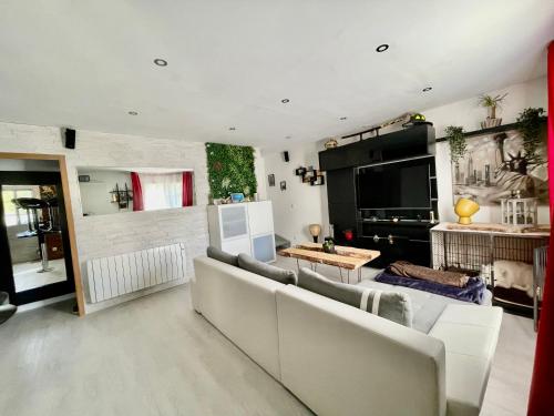 a living room with a couch and a tv at Chambres d'hôtes à thèmes à 2,4Km du parc in Magny-le-Hongre