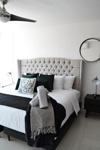 a white bedroom with a large bed with green pillows at Estudio Neen Zona Hotelera in Cancún