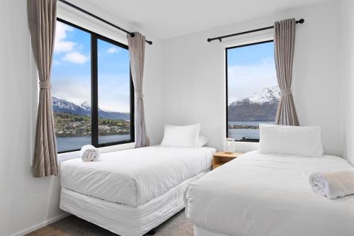 two beds in a room with a large window at Spa, Mountains & Lake in Queenstown