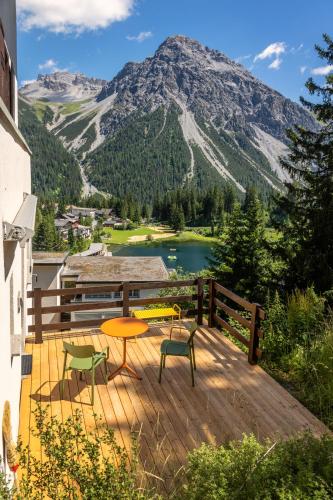 a deck with a table and chairs and a mountain at Belmont- Apartment Haus in Arosa