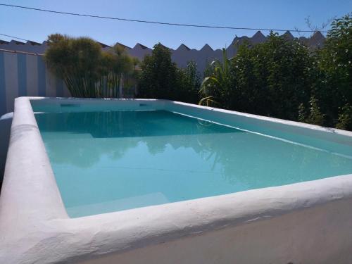 a swimming pool with blue water in a yard at Monte da Rocha 3 Marias in São Bartolomeu da Serra