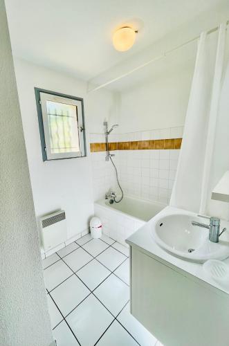 La salle de bains blanche est pourvue d'un lavabo et d'une baignoire. dans l'établissement Duplex T3 2 étoiles bord de lac 65mcarrés, à Biscarrosse