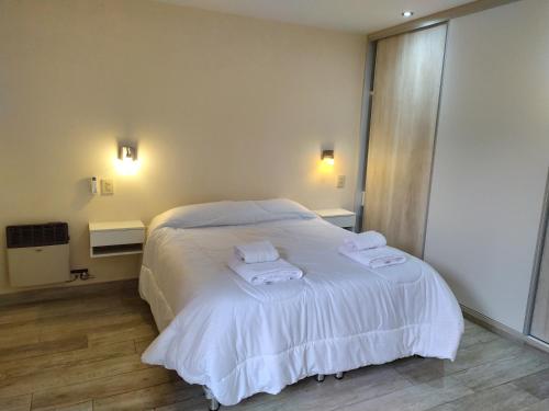 Un dormitorio con una cama blanca con toallas. en La Terraza Apartment: lujoso, amplio y ubicado en microcentro. en San Rafael