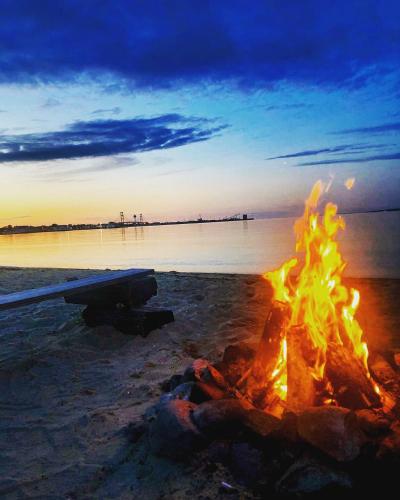 a bonfire on the beach with the ocean in the background at Beach House Lakeside Cottages in Mackinaw City