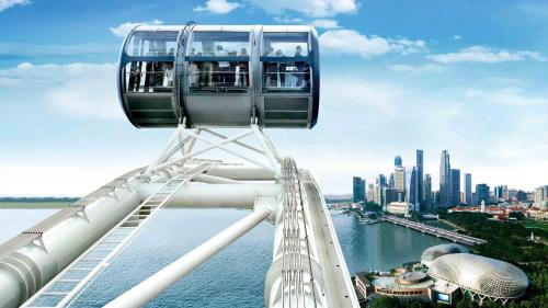 a roller coaster over the water with a city at Holiday Inn Singapore Atrium by IHG in Singapore
