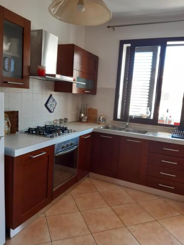 uma cozinha com armários de madeira e um forno com placa de fogão em A casa di Loretta em Terrasini