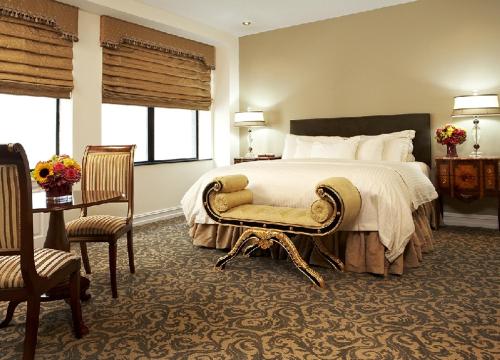 a large bedroom with a bed and a chair and windows at The Kimberly Hotel in New York