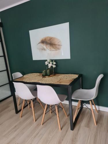 czarny stół jadalny z białymi krzesłami i obrazem w obiekcie Green Loft Apartament w Białej Podlaskiej