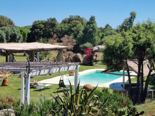 a swimming pool in a yard with a tree at La Quercia della Gallura in Luogosanto