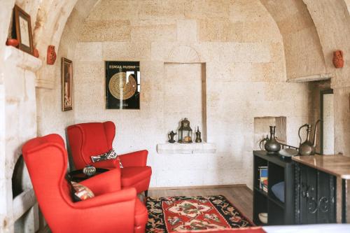 a living room with two red chairs and a rug at Elaa Cave Hotel in Ortahisar