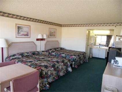 a hotel room with two beds and a desk at El Dorado Inn Suites - Nogales in Nogales