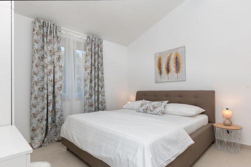 a bedroom with a bed with white sheets and a window at Villa Pinia Fazana in Fažana