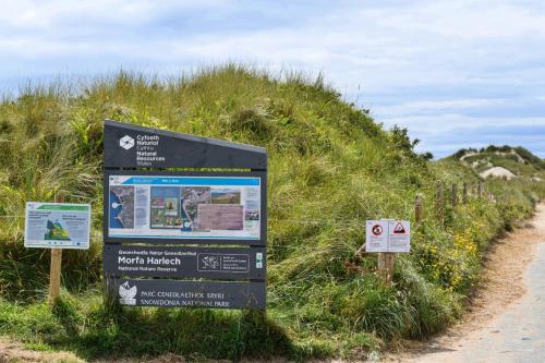 a sign in the grass next to a dirt road at Finest Retreats - Golygfa o'r Castell - Castle Views in Harlech