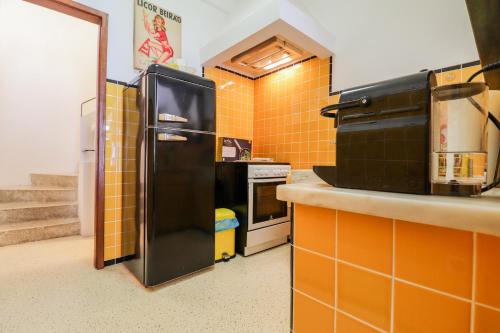 a black refrigerator in a kitchen with orange tiled walls at Casa da Fonte - Vintage House and Rooftop in Figueira da Foz