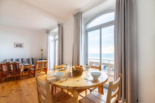 une salle à manger avec une table et une grande fenêtre dans l'établissement Séjour les pieds dans l'eau à Pléneuf-Val-André, à Pléneuf-Val-André