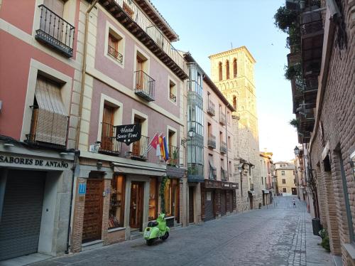 a green scooter parked on a street next to buildings at Hostal Santo Tomé in Toledo