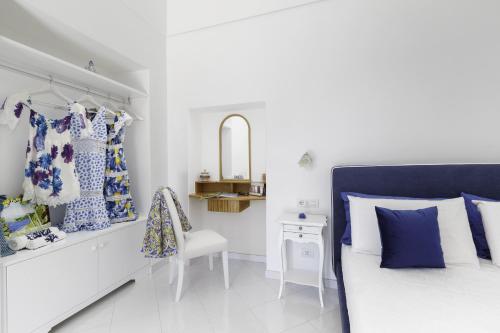 a white bedroom with a bed and a chair at Estate4home - Villa Settemari Scrigno in Positano