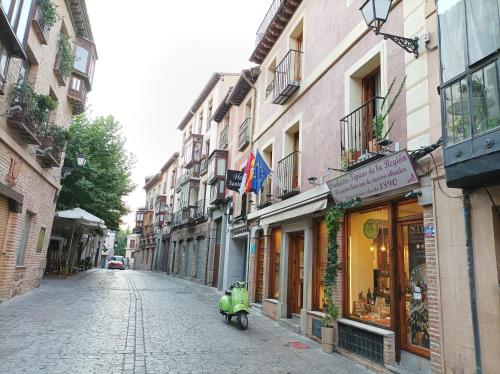 a small green scooter parked on a cobblestone street at Hostal Santo Tomé in Toledo