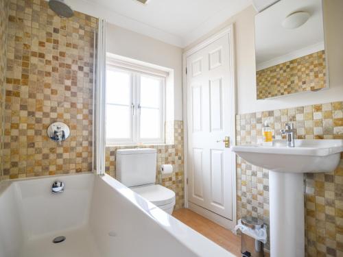 a bathroom with a tub and a sink and a toilet at Seagull Cottage in Lyme Regis