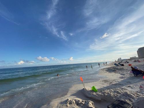 a sandy beach with people in the water and the ocean at LIVE ON ISLAND TIME! GREAT GULF SHORES BEACH CONDO, VERY NICE in Gulf Shores