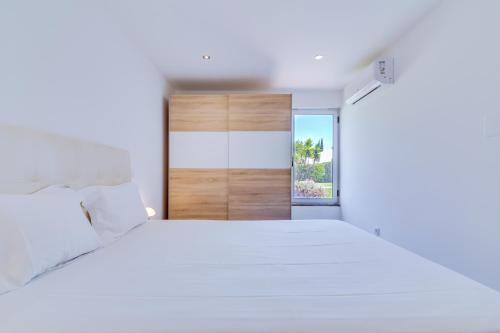 a white bedroom with a large bed and an open door at AL - Barracuda Village in Vilamoura