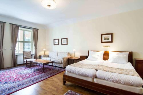 a bedroom with a bed and a couch and a chair at Mayfair Hotel Tunneln in Malmö