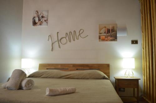 a bedroom with a bed with a home sign on the wall at il Cigno Reale-Green-Rooms Leasing Touristic Ragusa in Chiaramonte Gulfi