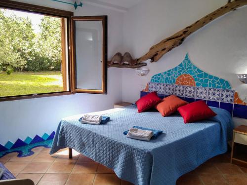 - une chambre avec un lit bleu avec des oreillers rouges et une fenêtre dans l'établissement Cuccuru Relax - B IUN Q9882, à Orosei