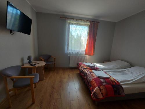 a bedroom with a bed and a table and a television at Pokoje Gościnne Maczek in Sztutowo